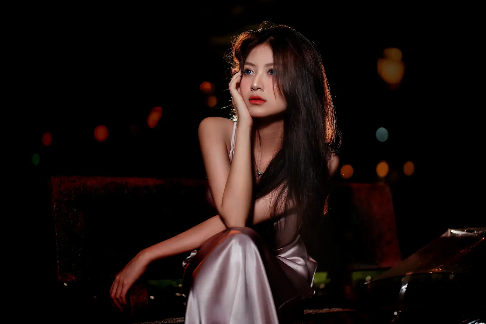Femme asiatique en robe de satin élégante, assise dans une lumière douce — OAFDating rencontres premium