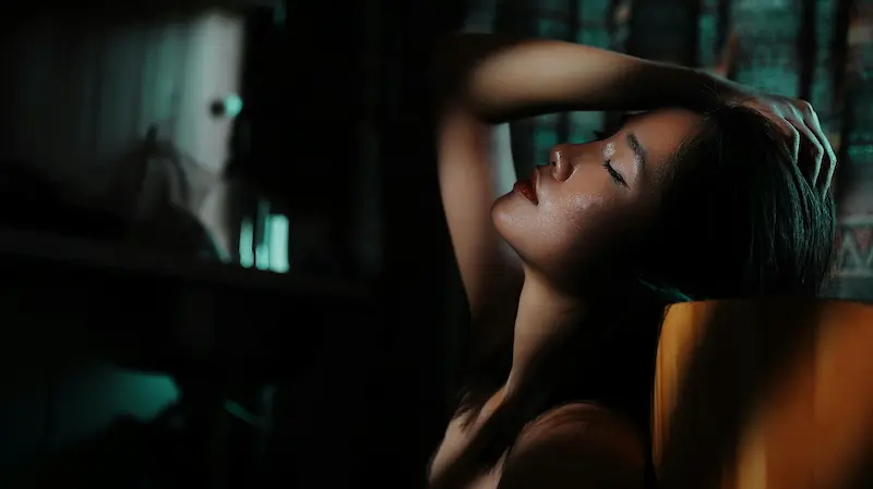 Asian woman in cinematic low light, eyes closed, intimate and atmospheric — selective access on OAFDating